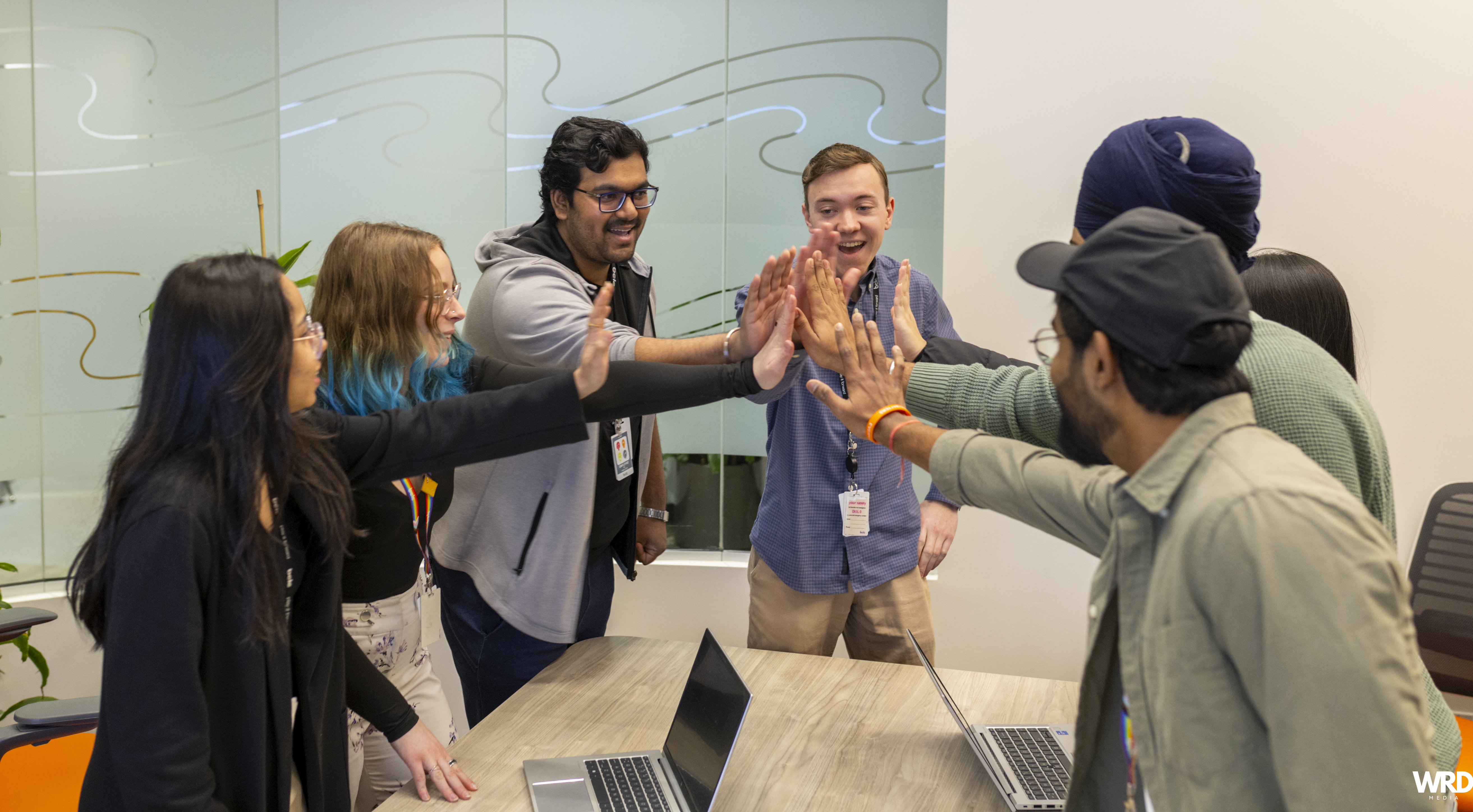 A group of colleagues high-five each other in an office.